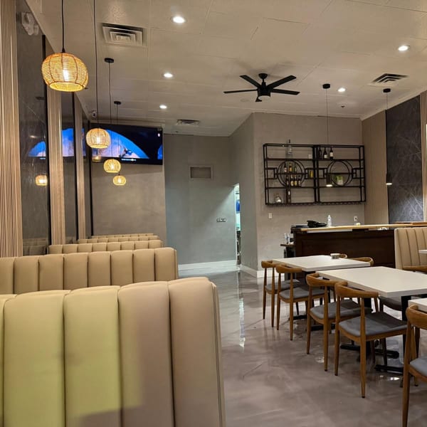 Interior of Biryani Pot Chandler, featuring booth seating, tables, and a bar area with decorative lighting.